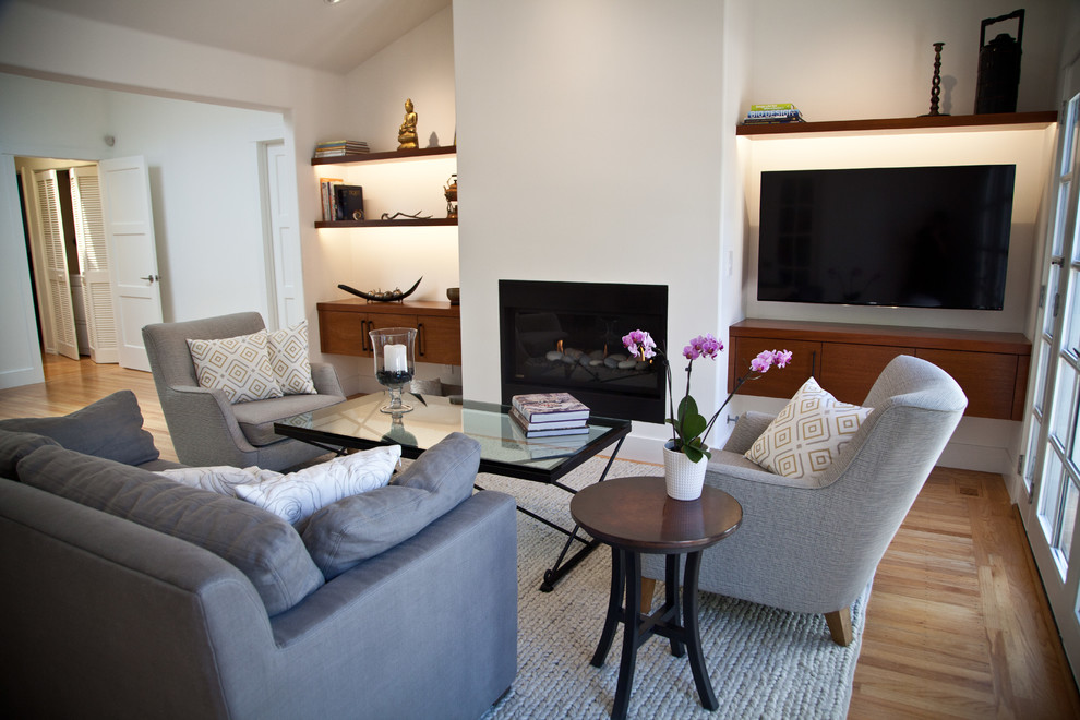 Photo of a medium sized contemporary open plan games room in San Francisco with white walls, light hardwood flooring, a ribbon fireplace, a plastered fireplace surround, a wall mounted tv and brown floors.