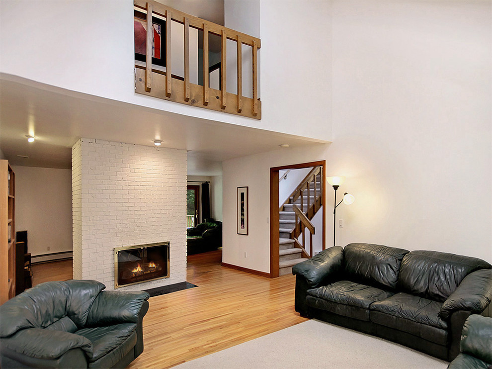 На фото: огромная открытая гостиная комната в современном стиле с белыми стенами, паркетным полом среднего тона, двусторонним камином и фасадом камина из кирпича с