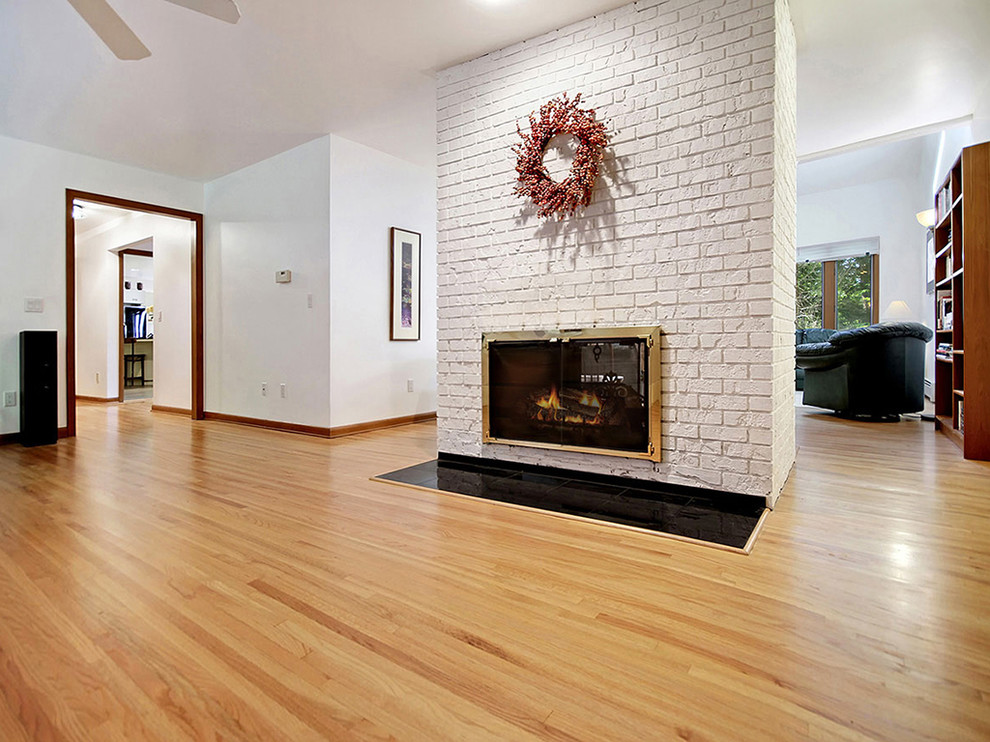 Inspiration for a huge contemporary open concept medium tone wood floor family room remodel in New York with white walls, a two-sided fireplace and a brick fireplace