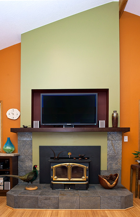 Cette photo montre une salle de séjour tendance de taille moyenne et ouverte avec une bibliothèque ou un coin lecture, un mur orange, parquet clair, une cheminée standard, un manteau de cheminée en pierre et un téléviseur fixé au mur.