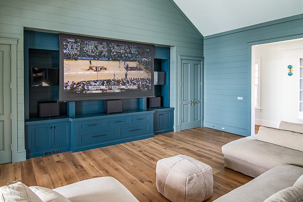 Modelo de sala de estar cerrada costera de tamaño medio sin chimenea con televisor colgado en la pared, suelo de madera clara, paredes azules y suelo marrón