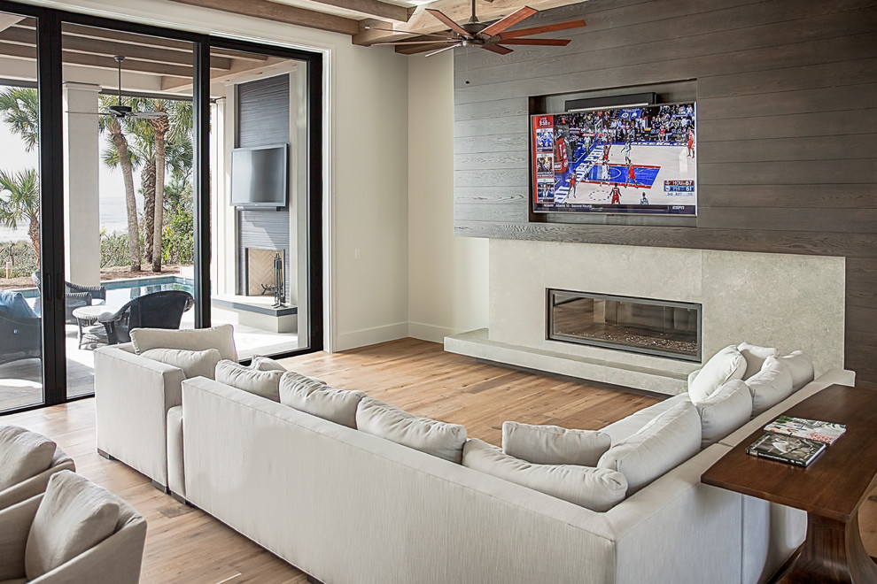 Идея дизайна: большая изолированная гостиная комната в морском стиле с телевизором на стене, белыми стенами, светлым паркетным полом, горизонтальным камином, фасадом камина из бетона и коричневым полом