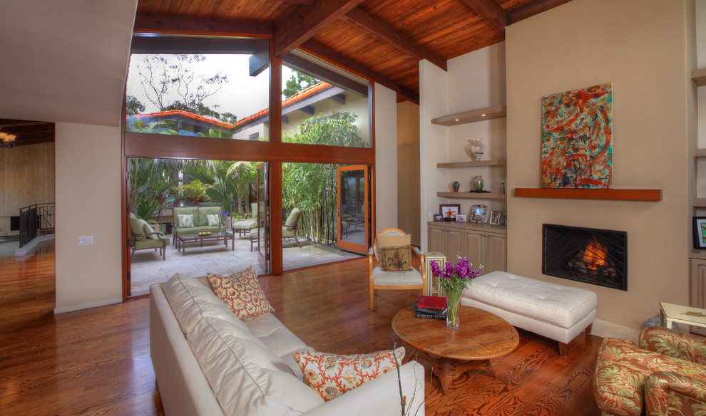Foto de sala de estar abierta tropical sin televisor con paredes beige, suelo de madera en tonos medios y todas las chimeneas