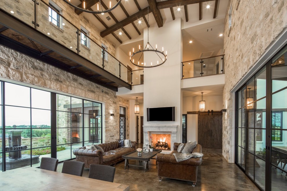 Example of a large trendy loft-style concrete floor family room design in Austin with beige walls, a standard fireplace and a stone fireplace