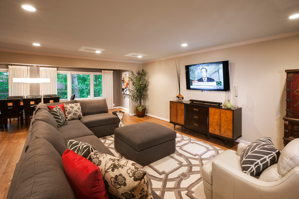 Ejemplo de sala de estar abierta actual grande sin chimenea con paredes grises, suelo de madera en tonos medios y televisor colgado en la pared