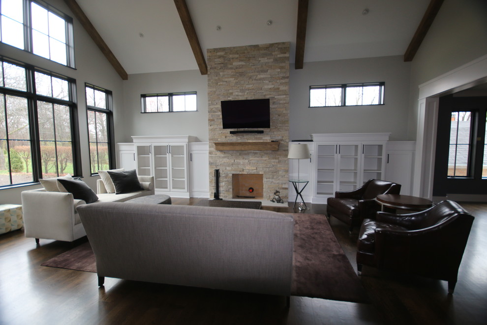 На фото: изолированная гостиная комната среднего размера в стиле неоклассика (современная классика) с серыми стенами, темным паркетным полом, стандартным камином, фасадом камина из камня, телевизором на стене и коричневым полом с