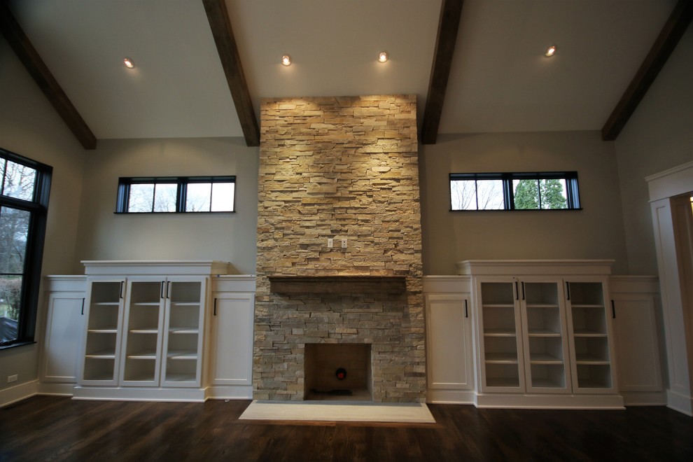 На фото: изолированная гостиная комната среднего размера в стиле неоклассика (современная классика) с серыми стенами, темным паркетным полом, стандартным камином, фасадом камина из камня, телевизором на стене и коричневым полом