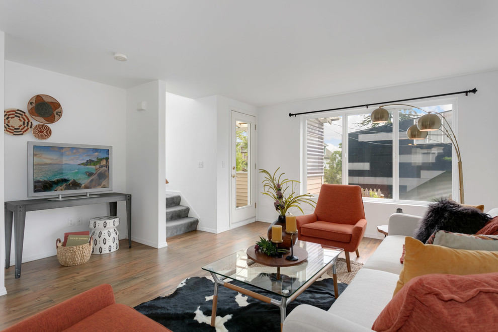 Immagine di un soggiorno minimal di medie dimensioni e chiuso con pareti bianche, parquet chiaro, TV autoportante e pavimento marrone
