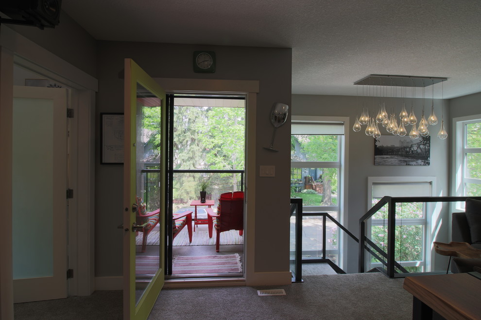 Imagen de sala de estar con barra de bar cerrada actual de tamaño medio sin chimenea con paredes grises, moqueta, televisor colgado en la pared y suelo beige