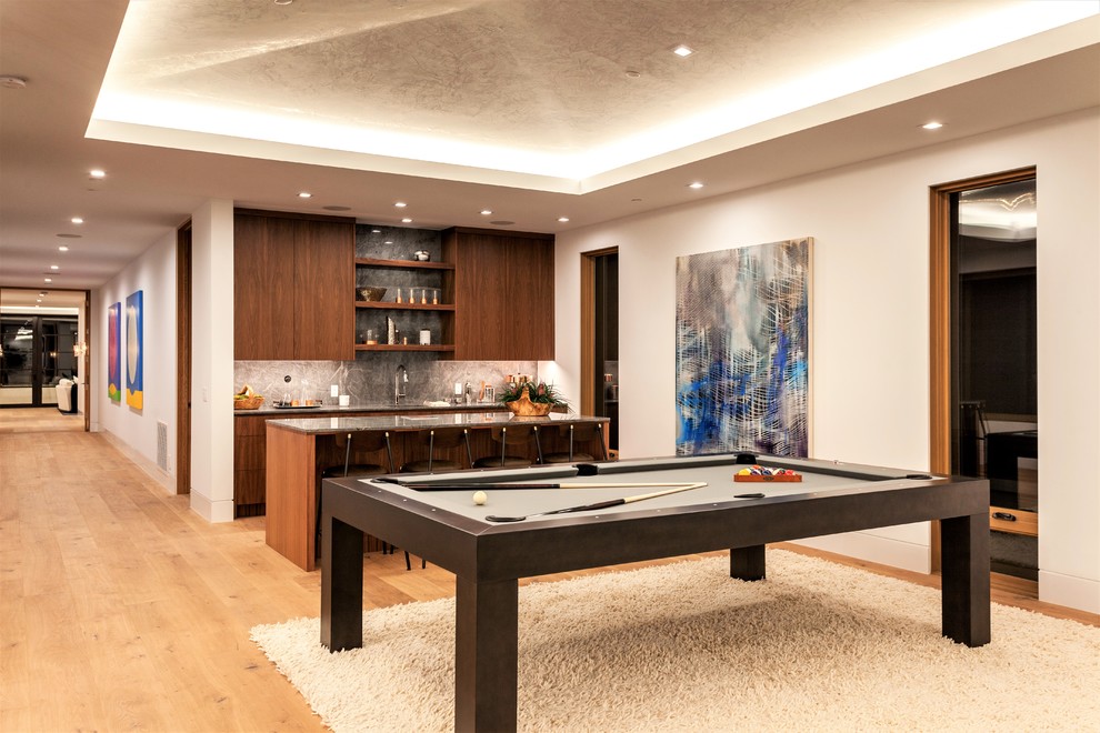 Imagen de sala de juegos en casa abierta contemporánea grande sin chimenea con paredes blancas, suelo de madera clara, televisor colgado en la pared y suelo beige