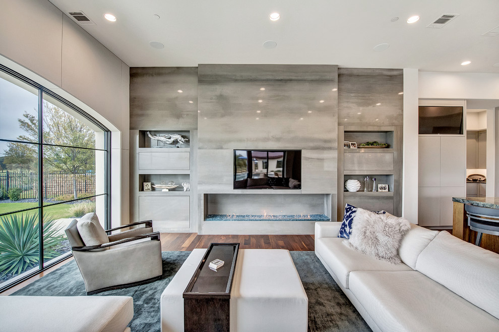 Geräumiges, Offenes Modernes Wohnzimmer mit weißer Wandfarbe, braunem Holzboden, Kamin, Kaminumrandung aus Stein, Multimediawand und braunem Boden in Orange County