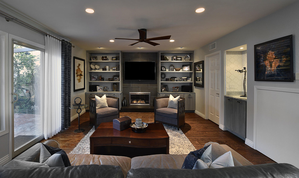Идея дизайна: изолированная гостиная комната среднего размера в стиле неоклассика (современная классика) с серыми стенами, темным паркетным полом, стандартным камином, фасадом камина из плитки, телевизором на стене и коричневым полом