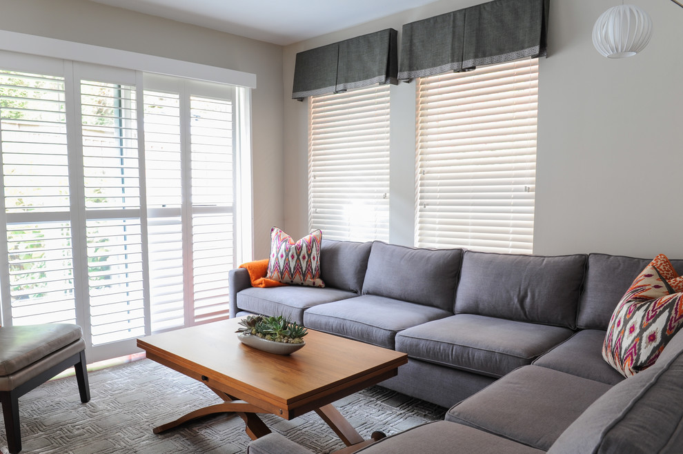 Imagen de sala de estar abierta contemporánea pequeña sin chimenea con paredes grises, suelo de madera en tonos medios y televisor colgado en la pared