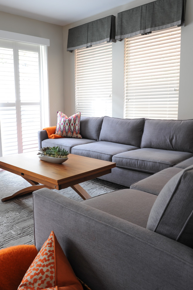Imagen de sala de estar abierta contemporánea pequeña sin chimenea con paredes grises, suelo de madera en tonos medios y televisor colgado en la pared