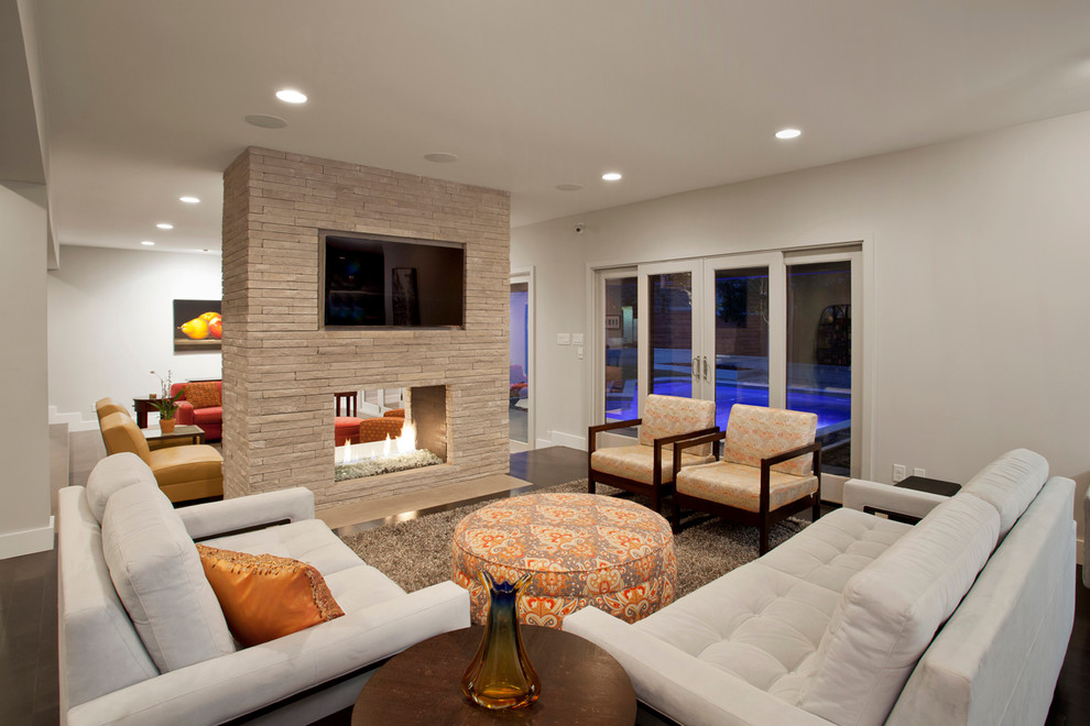 На фото: гостиная комната в современном стиле с двусторонним камином с