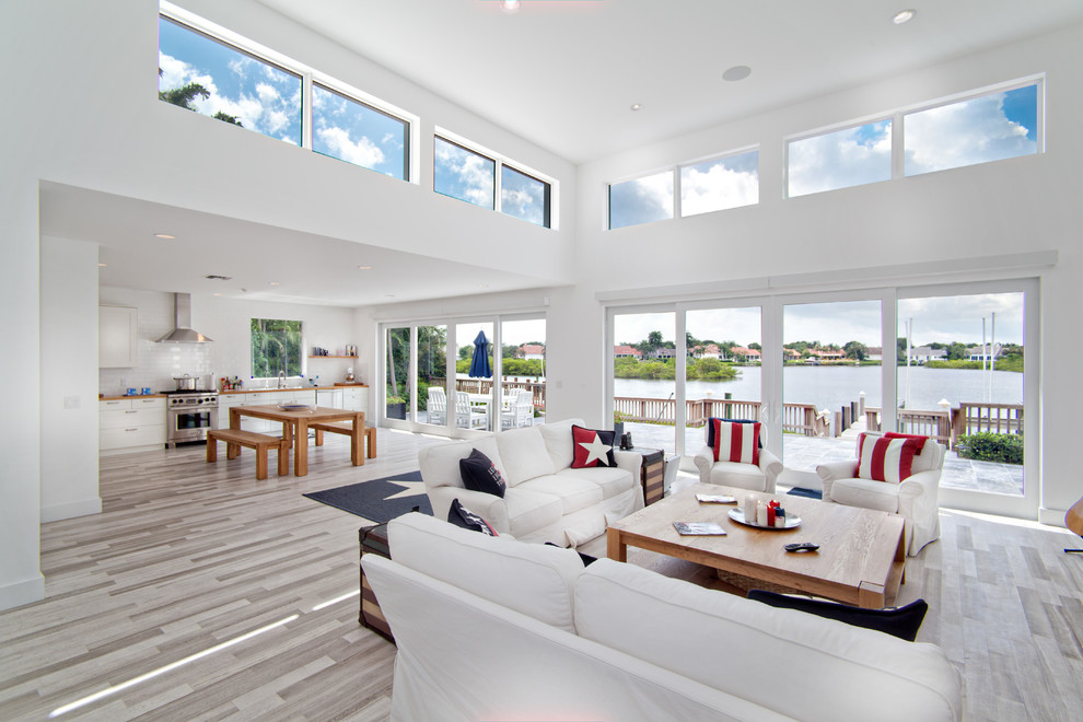 Offenes, Fernseherloses Maritimes Wohnzimmer ohne Kamin mit weißer Wandfarbe, braunem Holzboden und beigem Boden in Miami