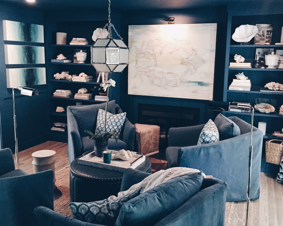 Immagine di un soggiorno eclettico di medie dimensioni e aperto con libreria, pareti blu, parquet scuro, camino classico, cornice del camino in metallo e nessuna TV
