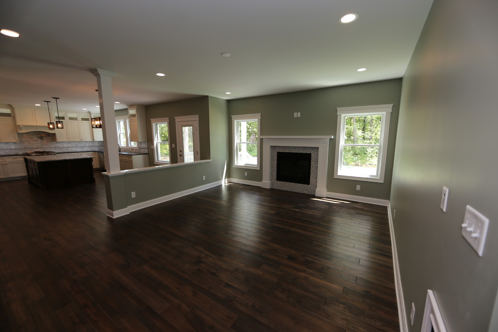 Cette image montre une grande salle de séjour craftsman ouverte avec un mur vert, un sol en bois brun, une cheminée standard, un manteau de cheminée en carrelage, un téléviseur fixé au mur et un sol bleu.