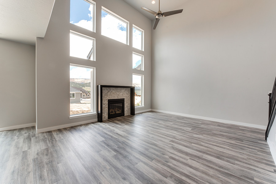Inspiration for a medium sized classic open plan games room in Salt Lake City with grey walls, vinyl flooring, a standard fireplace, a tiled fireplace surround and brown floors.