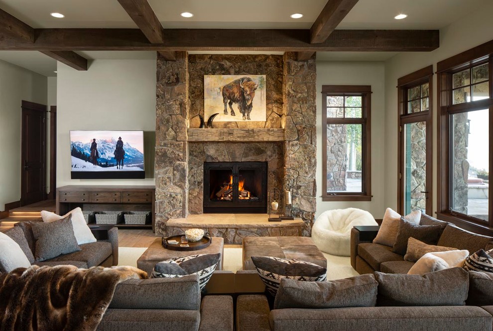 Imagen de sala de estar rústica con paredes blancas, suelo de madera en tonos medios, todas las chimeneas, marco de chimenea de piedra y suelo marrón