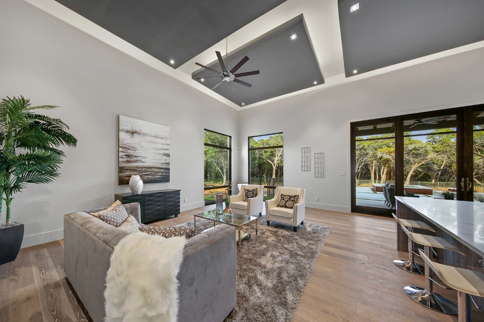 Example of a large trendy open concept light wood floor and gray floor family room design in Austin with a bar, gray walls, no fireplace and no tv