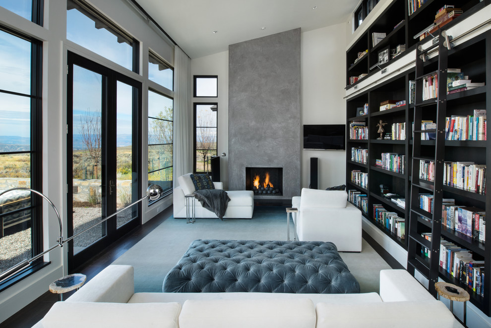 Inspiration for a medium sized contemporary open plan games room in Denver with a reading nook, white walls, a standard fireplace, a concrete fireplace surround, a wall mounted tv, dark hardwood flooring and brown floors.