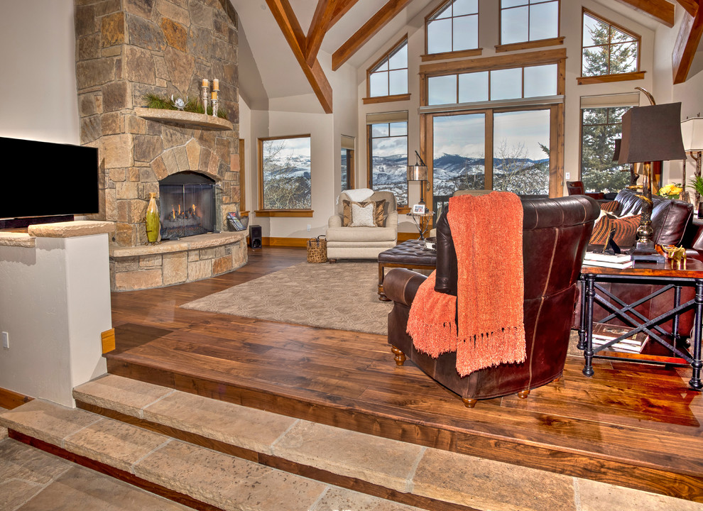 Large mountain style open concept medium tone wood floor family room photo in Denver with beige walls, a standard fireplace, a stone fireplace and a tv stand