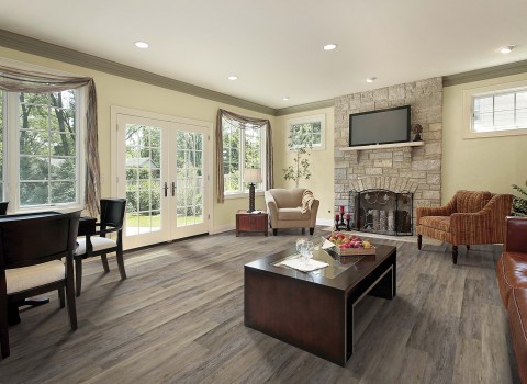 Cette image montre une salle de séjour traditionnelle de taille moyenne et ouverte avec un sol en vinyl, un mur beige, une cheminée standard, un manteau de cheminée en pierre, un téléviseur indépendant et un sol gris.
