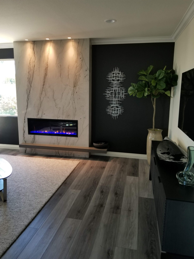 Photo of a modern open plan games room in Orange County with multi-coloured walls, vinyl flooring, a hanging fireplace, a stone fireplace surround and a wall mounted tv.