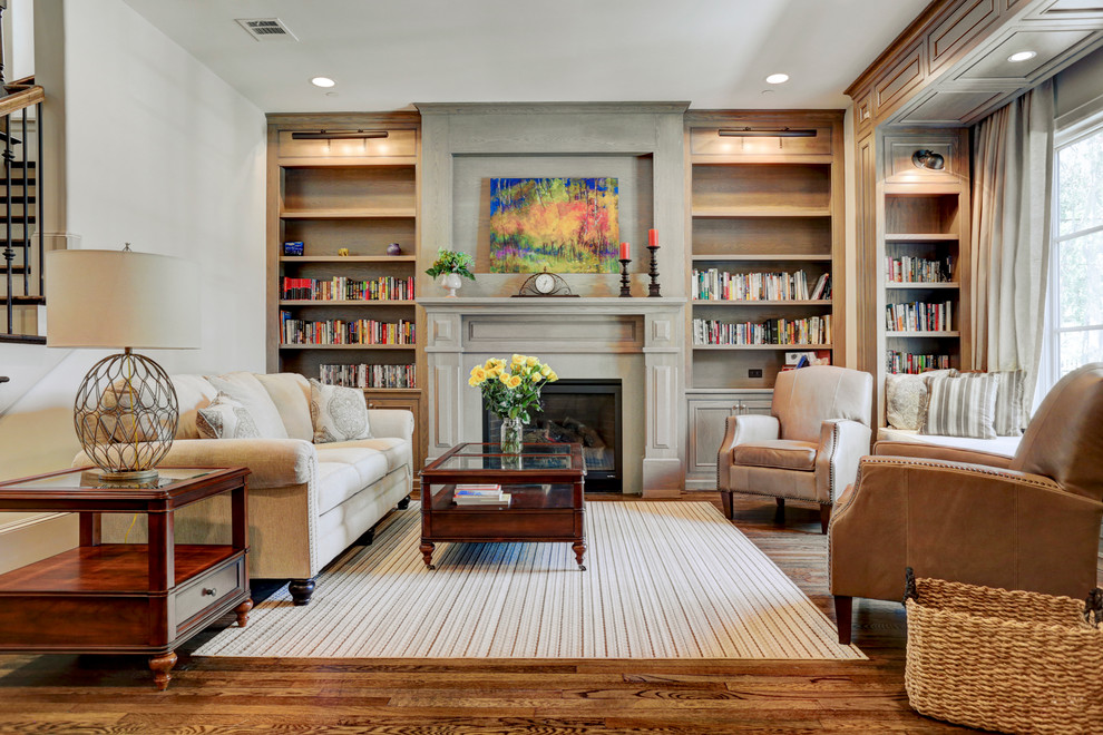 Imagen de sala de estar con biblioteca cerrada tradicional grande sin televisor con paredes beige, suelo de madera en tonos medios, todas las chimeneas y marco de chimenea de madera