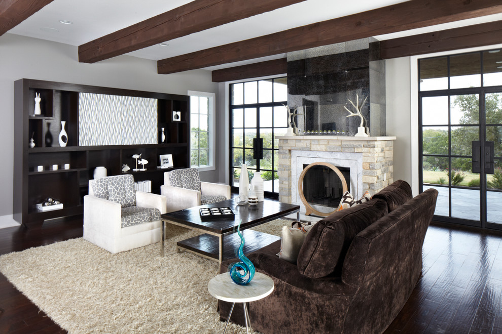 Источник вдохновения для домашнего уюта: большая изолированная гостиная комната в стиле неоклассика (современная классика) с серыми стенами, темным паркетным полом, стандартным камином, скрытым телевизором и фасадом камина из камня