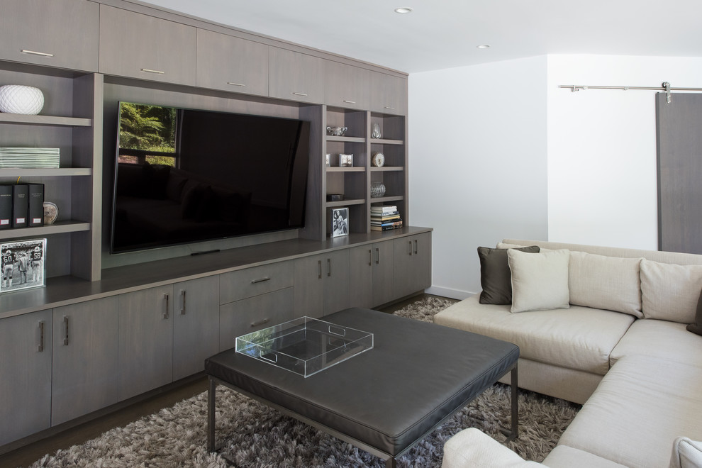 Ejemplo de sala de estar abierta moderna grande con paredes grises, suelo de madera clara, pared multimedia y suelo gris