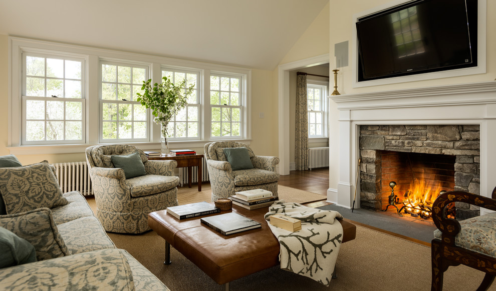Inspiration for a timeless dark wood floor family room remodel in New York with beige walls, a standard fireplace, a stone fireplace and a wall-mounted tv