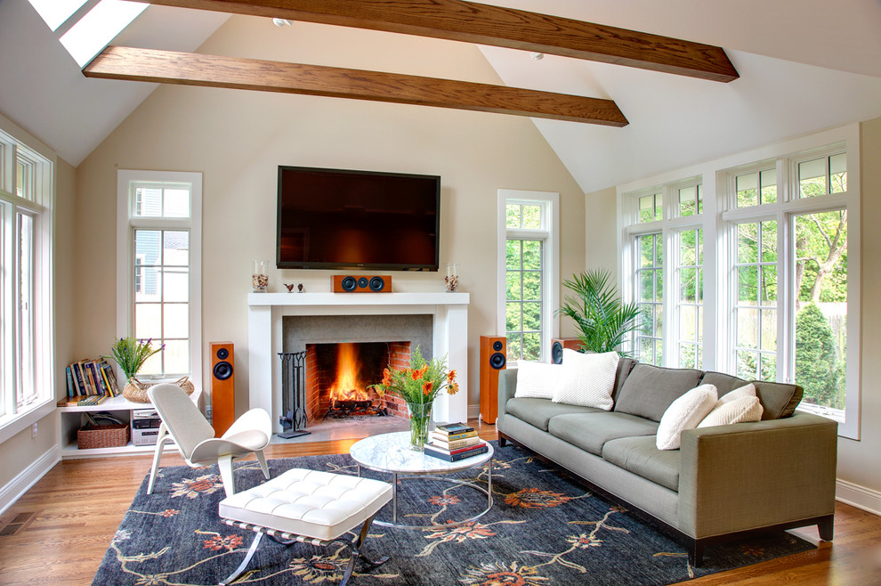 Immagine di un grande soggiorno tradizionale chiuso con pareti beige, camino classico, pavimento in legno massello medio e TV a parete