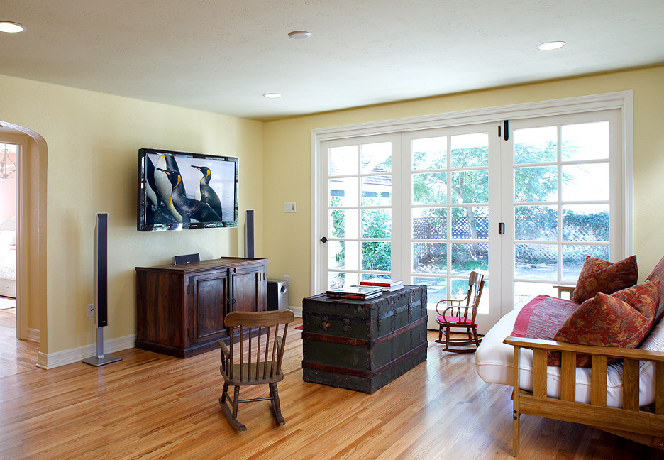 Diseño de sala de estar cerrada campestre de tamaño medio sin chimenea con paredes amarillas, suelo de madera clara y televisor colgado en la pared