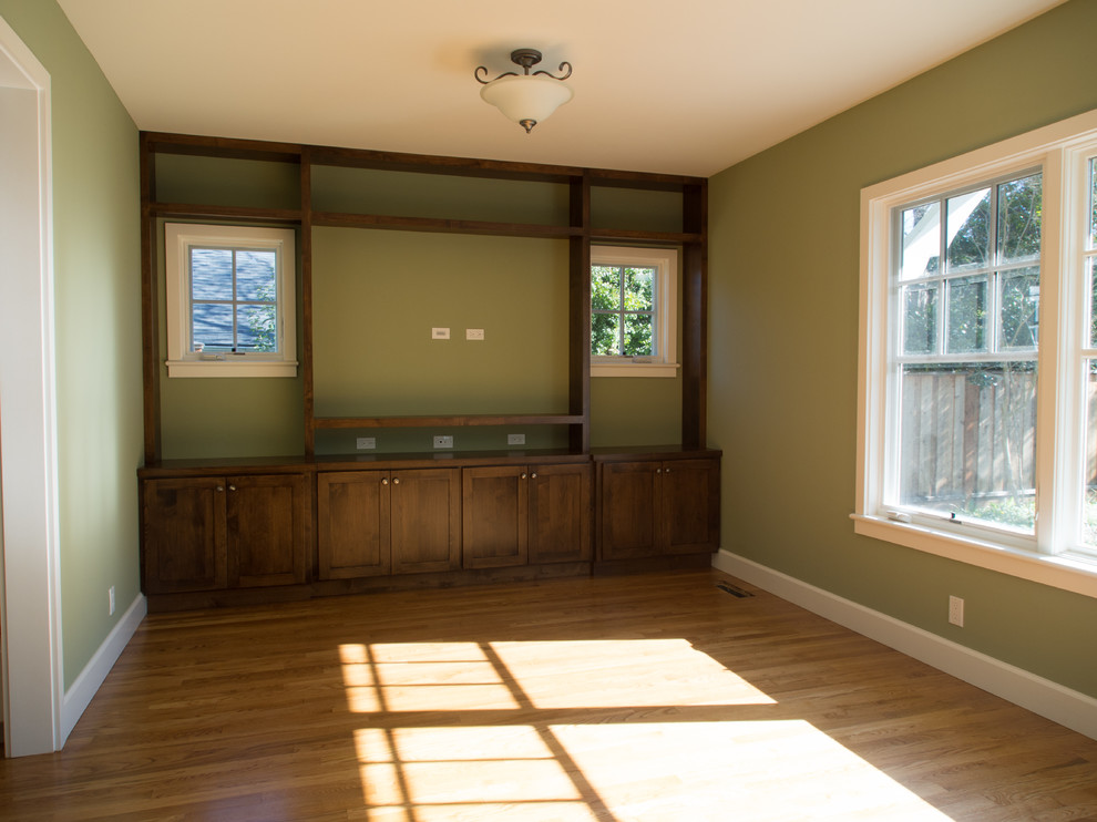 Réalisation d'une salle de séjour tradition fermée avec un mur vert, un sol en bois brun, aucune cheminée et un téléviseur encastré.