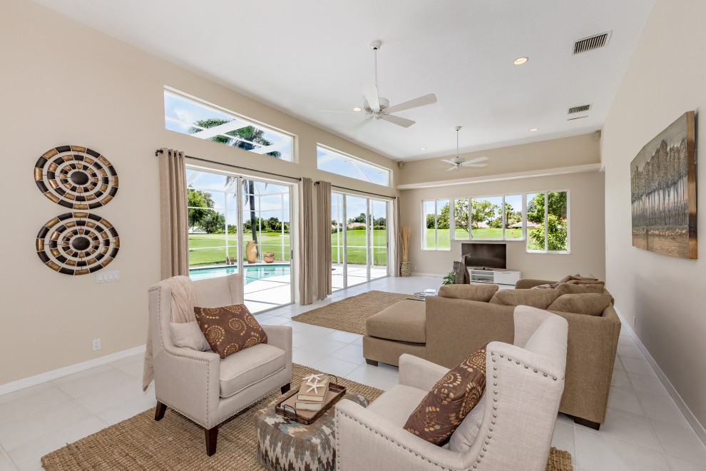 Large mediterranean open plan games room in Tampa with beige walls, porcelain flooring, a freestanding tv and white floors.