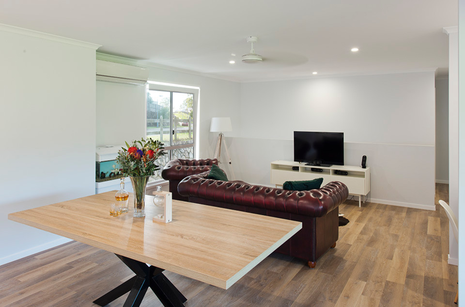 This is an example of a medium sized classic open plan games room in Sunshine Coast with white walls, vinyl flooring, a freestanding tv and brown floors.