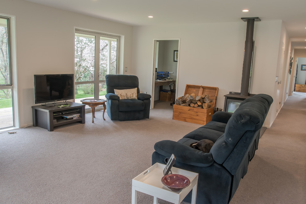 Mittelgroßes, Offenes Landhausstil Wohnzimmer mit beiger Wandfarbe, Teppichboden, Kamin, gefliester Kaminumrandung und freistehendem TV in Christchurch