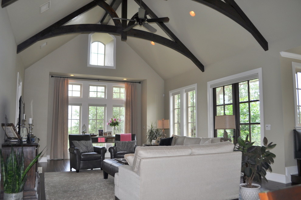 Imagen de sala de estar abierta clásica grande con paredes beige, suelo de madera oscura y alfombra