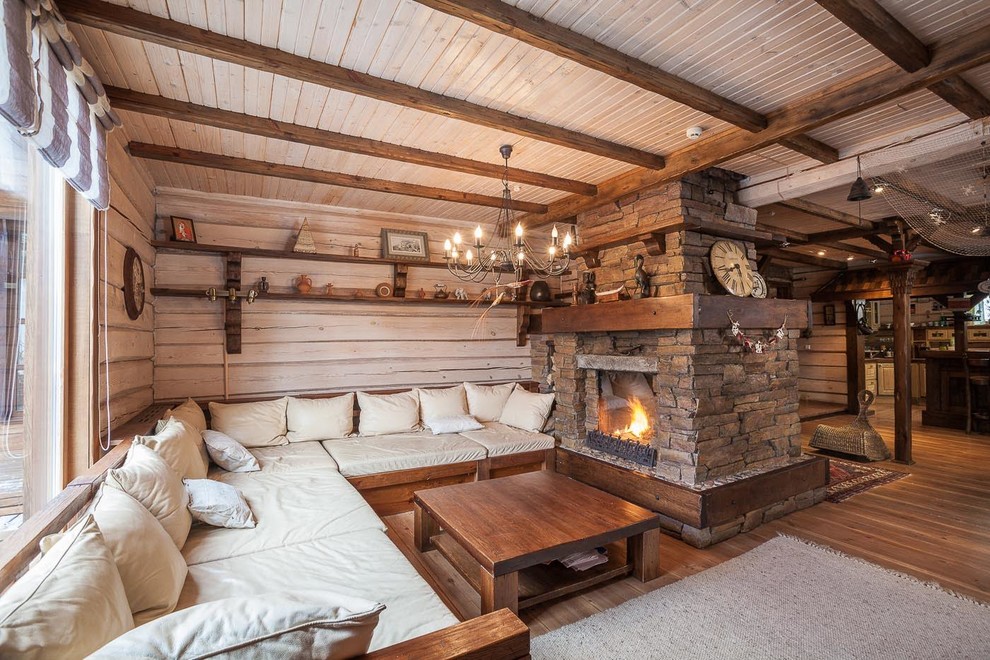 Idées déco pour une grande salle de séjour montagne fermée avec un mur beige, un sol en bois brun, un poêle à bois, un manteau de cheminée en pierre et un téléviseur indépendant.