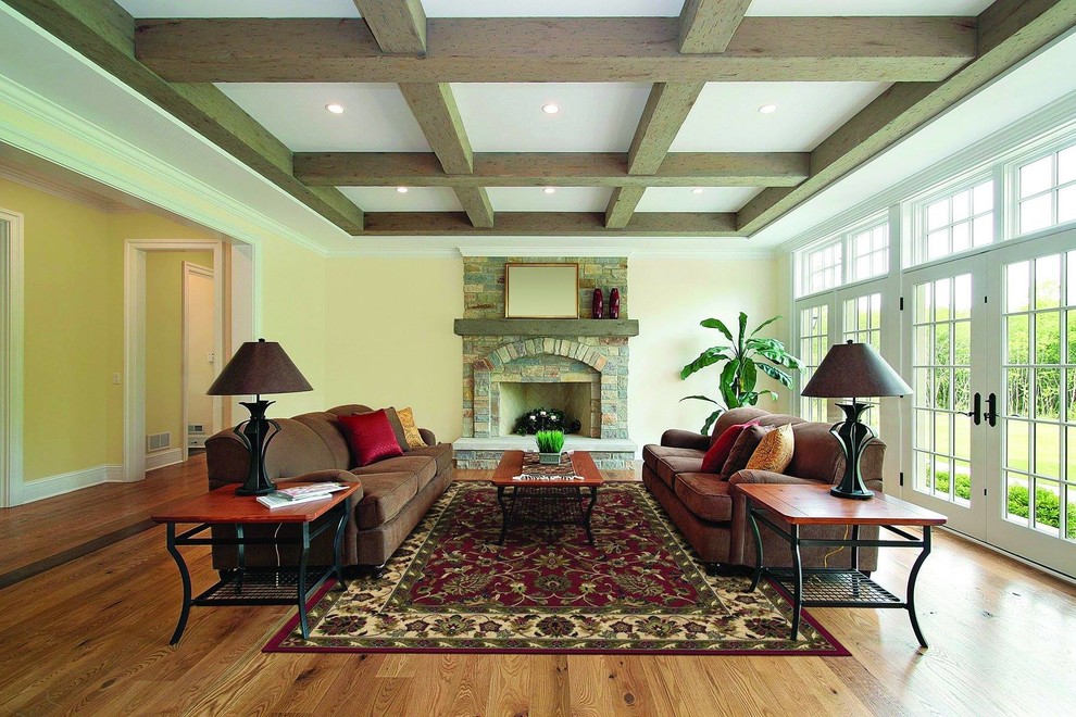 Großes, Fernseherloses, Offenes Klassisches Wohnzimmer mit gelber Wandfarbe, braunem Holzboden, Kamin, Kaminumrandung aus Stein und braunem Boden in Houston