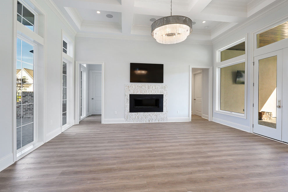 Inspiration for a medium sized classic open plan games room in New Orleans with grey walls, laminate floors, a standard fireplace, a tiled fireplace surround, a wall mounted tv, brown floors and a coffered ceiling.