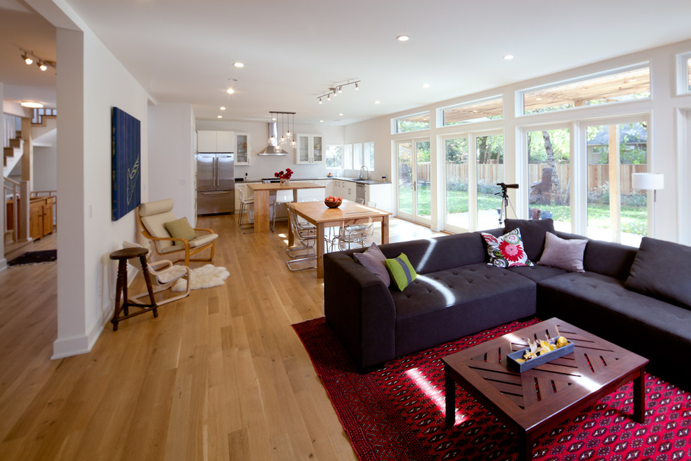 Imagen de sala de estar abierta actual con suelo de madera en tonos medios y alfombra