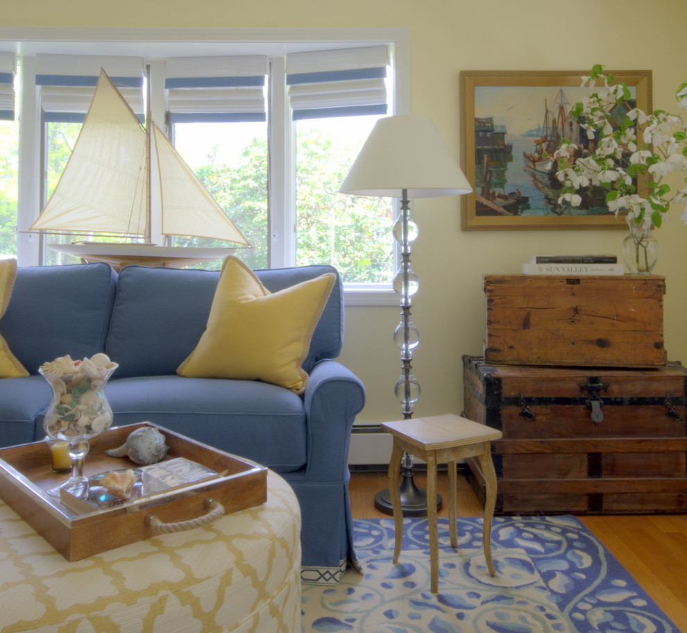 Imagen de sala de estar cerrada marinera de tamaño medio sin chimenea y televisor con paredes amarillas y suelo de madera en tonos medios