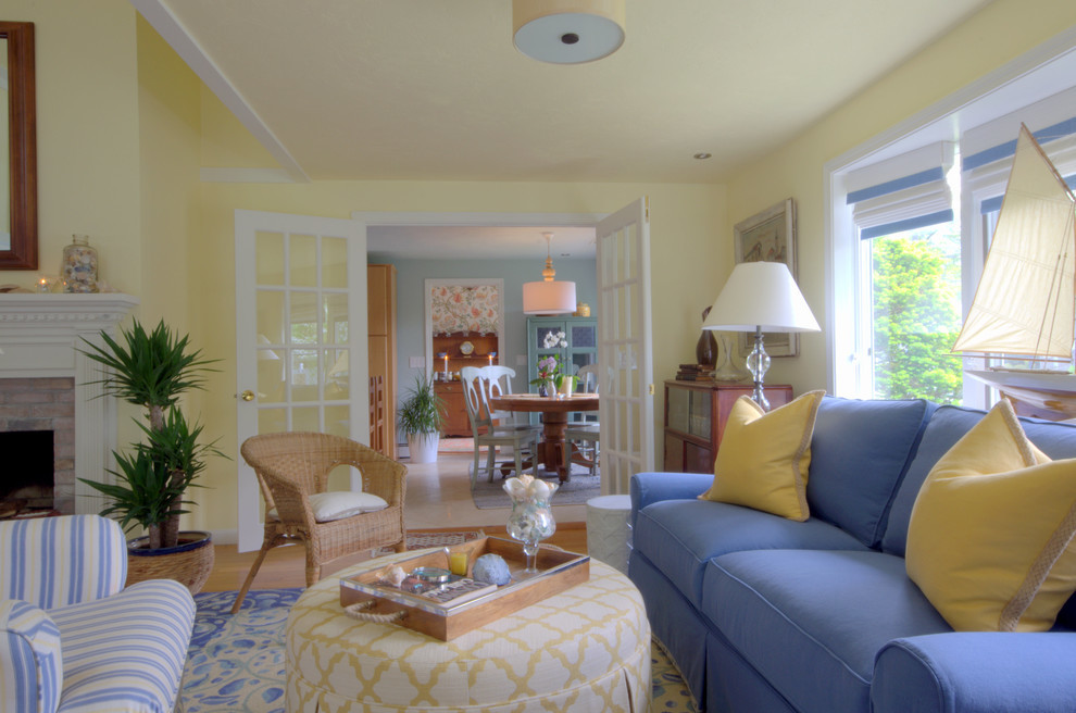 На фото: двухуровневая гостиная комната среднего размера в морском стиле с желтыми стенами, паркетным полом среднего тона, стандартным камином и фасадом камина из бетона без телевизора с