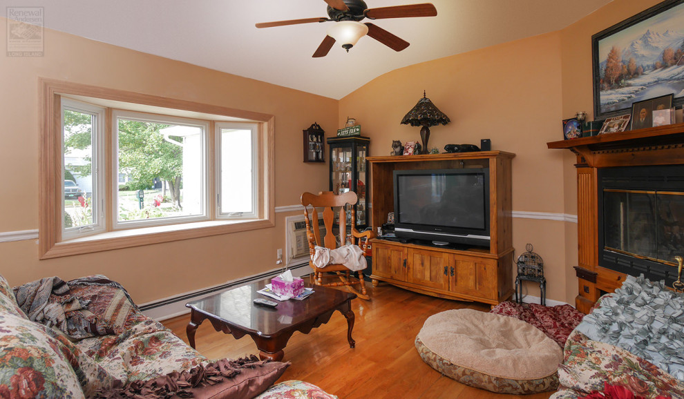 На фото: изолированная гостиная комната среднего размера с оранжевыми стенами, паркетным полом среднего тона, угловым камином, фасадом камина из дерева, отдельно стоящим телевизором и сводчатым потолком с