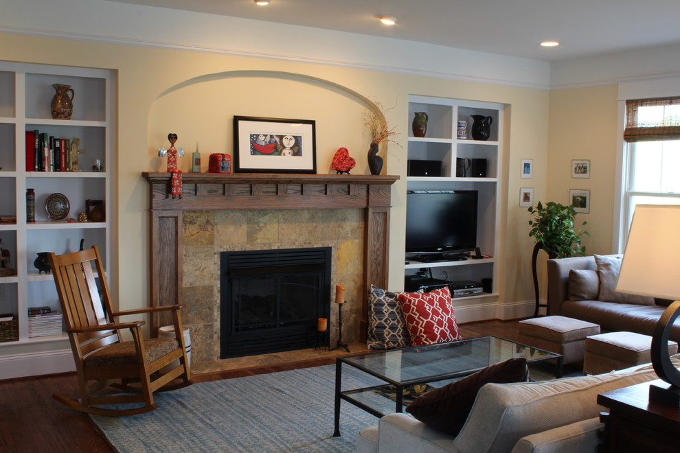 Стильный дизайн: открытая гостиная комната в классическом стиле с желтыми стенами, темным паркетным полом, стандартным камином, фасадом камина из плитки и отдельно стоящим телевизором - последний тренд