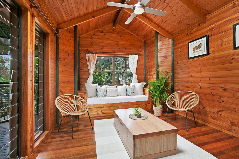 Foto di un soggiorno tropicale con pareti arancioni, pavimento in legno massello medio, nessun camino e nessuna TV