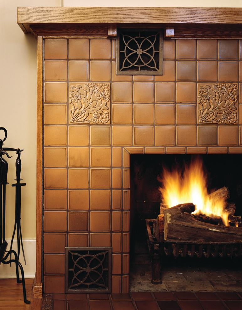 Réalisation d'une salle de séjour craftsman avec un mur jaune, un sol en bois brun, une cheminée standard, un manteau de cheminée en carrelage et un sol marron.